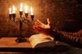 Religious female crossed hands in prayer with bible and candle