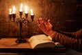 Religious female crossed hands in prayer with bible and candle Royalty Free Stock Photo