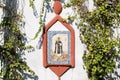 Religious image on a white wall surrounded by climbing plants