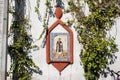 Religious image on a white wall surrounded by climbing plants