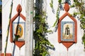 Religious images on a white wall surrounded by climbing plants