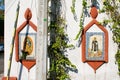 Religious images on a white wall surrounded by climbing plants