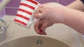 a religious Jewish woman washes her hands from a mug above the sink, alternately pouring netilat yadaim on each hand