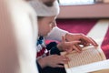 Religious Muslim Man teaching his little son to pray to God with Koran and rosary at mosque during ramadan Royalty Free Stock Photo