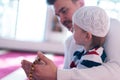 Religious Muslim Man teaching his little son to pray to God with Koran and rosary at mosque during ramadan Royalty Free Stock Photo