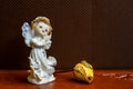 Religious still life: figurine of angel and an unopened bud of dry yellow rose  on  brown background. Decorative, composition. Royalty Free Stock Photo