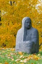 Religious stone figure of a woman against autumnal trees