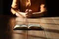 Religious woman praying over Bible at wooden table indoors, focus on book Royalty Free Stock Photo