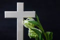 Religious wooden cross with white tulip flowers on a dark background. Condolence card. Place for text