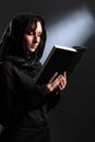 Religious young woman in headscarf reading bible