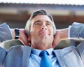 Relishing his success. a content businessman leaning back in his chair with his hands behind his head. Royalty Free Stock Photo