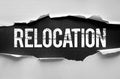 RELOCATION text revealed beneath torn paper with a rough, distressed font. Royalty Free Stock Photo