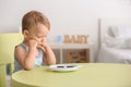 Reluctant little boy with cookies at table indoors