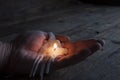 The remainder of a melted burning candle on a manÃ¢â¬â¢s hand. Love has melted. Darkness. On wooden background