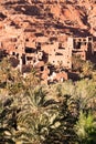 Remains of an ancient Moroccan village with its partially reduced adobe buildings and a group of palm trees in the foreground Royalty Free Stock Photo