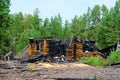 The remains of a burned wooden new house after a fire without a roof with charred logs in the forest of the Northern taiga. Royalty Free Stock Photo