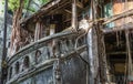 The remains of a derelict abandoned ancient house with antique stone stairs and tree roots