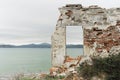 Remains of ruined old brick house and window without glass with view of beautiful blue clear sea and mountains, selective focus Royalty Free Stock Photo