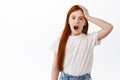 Remember forget. Cute redhead little girl, kid with long ginger hair and freckles forgot, holding hand on head and say Royalty Free Stock Photo