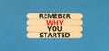 Remember why you started symbol. Concept word Remember why you started on beautiful wooden stick. Beautiful blue table blue