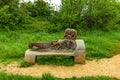 A remembrance bench sculpture along a path with green vegetation and trees
