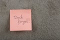 a reminder - don't forget written on color sticker notes on cement background