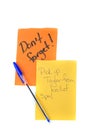 Reminder note. Blue pen on orange and yellow note pad page isolated over white - don't forget written on paper. Top down view Royalty Free Stock Photo