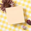 Reminder sticky note with dry flowers on yellow check pattern fabric background