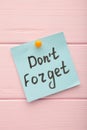 Reminder with text `Don`t forget` on a blue memo on pink background