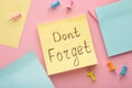 Reminder with text `Don`t forget` on a yellow memo on pink background