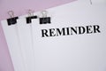 Reminder the text is written on a white piece of paper and a pink background Royalty Free Stock Photo