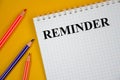 Reminder word written on white notepad and yellow background