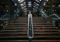 Modern grand stairs in converted historic industrial building with wood roof trusses and ceiling skylight windows. Adaptive reuse.