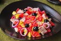 Remojon salad of blood oranges, potatoes, boiled salted fish and red onions on a black plate on a green concrete background.