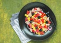 Remojon salad of blood oranges, potatoes, boiled salted fish and red onions on a black plate on a green concrete background.