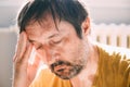 Remorse concept, regretful unkempt man at home in living room, lit by the morning sun