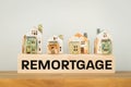 REMORTGAGE, a word written on a wooden block with miniature houses. Real estate business and financial concept, copy space