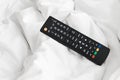 Remote on bed sheets Royalty Free Stock Photo