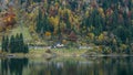 Remote building and colorful trees reflected in alpine lake. Autumn landscape. Royalty Free Stock Photo