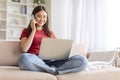 Remote business. Asian woman talking on phone and using laptop at home Royalty Free Stock Photo