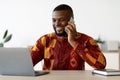 Remote Career. Young African Freelancer Man Talking On Cellphone At Home Office