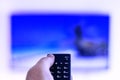 The remote control is in the hand of a man, directed to a large-screen TV Royalty Free Stock Photo