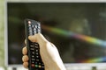 Remote control in the hand of the man tv in the background in blur Royalty Free Stock Photo
