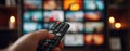 The remote control in hand with multiple screens displayed in the background. AI generated image Royalty Free Stock Photo
