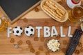 Remote control, slate, snacks, drinks and football word arranged on table