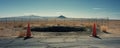 Remote desert road with large pothole and traffic cones. Royalty Free Stock Photo