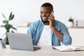 Remote Job. Black Freelancer Guy Using Cellphone And Laptop At Home Office Royalty Free Stock Photo