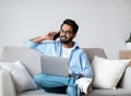 Remote Job. Eastern Man Talking On Cellphone And Using Laptop At Home Royalty Free Stock Photo