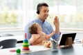 Father in headset working at home office with baby