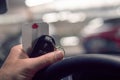 Remote key and parking ticket in a hand of a driver on a steering wheel. Car park out of focus in the background Royalty Free Stock Photo